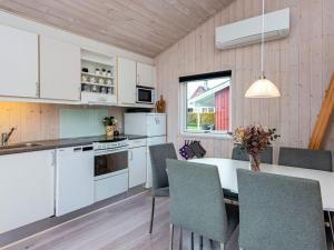 eine Küche mit weißen Schränken und einem Tisch mit Stühlen in der Unterkunft Holiday home Sydals LXXI in Mommark