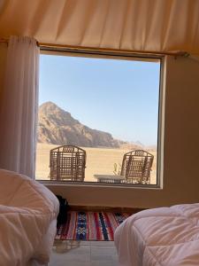a bedroom with a view of the desert from a window at Ammar Rum Camp and jeep tour in Wadi Rum
