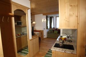 a kitchen with wooden cabinets and a living room at Apartments Sol E Nef in Rocca Pietore