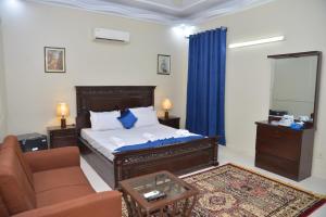 ein Schlafzimmer mit einem Bett, einem Sofa und einem Spiegel in der Unterkunft Diamond Lodge in Karatschi