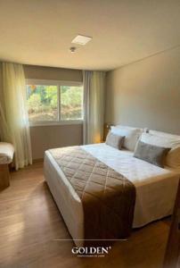 a bedroom with a large bed with a window at Golden Gramado Lagueto Resort in Gramado