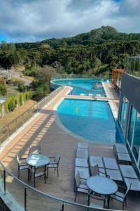 uma varanda com mesas e cadeiras ao lado de uma piscina em Golden Gramado Lagueto Resort em Gramado