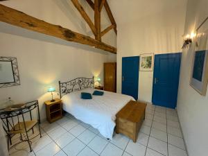 a bedroom with a bed with blue doors and a table at LE GOLURET Chambres & Table d'hôtes - Espace Bien Être in Couvignon