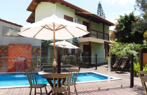 a table with an umbrella next to a swimming pool at Pousada Do Capitão in Florianópolis