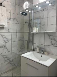 a white bathroom with a sink and a shower at Breaza Comfort Apartment in Breaza