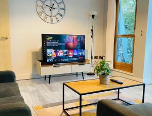 a living room with a large television and a clock at stylish two bed in the heart of the city in Birmingham