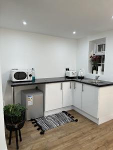 a kitchen with white cabinets and a microwave on a counter at Touchwood in Isleworth