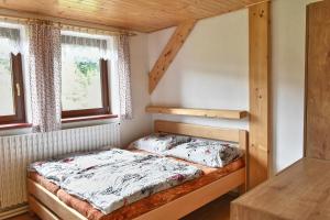 a small bedroom with a bed and two windows at Chalupa Orlička in Výprachtice