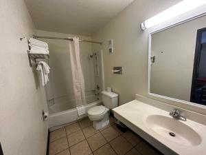 ein Badezimmer mit einem Waschbecken, einem WC und einem Spiegel in der Unterkunft Simple Rewards Inn in Ruidoso