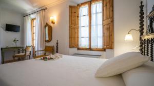a bedroom with a large white bed and windows at Juma Historic Hotel in Pollença