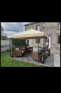 un patio con sillas y una sombrilla grande en Maison Les Berrys, en Bourganeuf