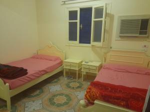 a bedroom with two beds and two windows at Grand house in Nag` el-Ramla