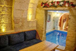 Calypso Cave Suites في أوروغوب: حمام سباحة في غرفة مع أريكة وطاولة