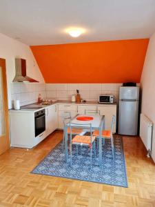 een keuken met een tafel en stoelen en een oranje muur bij Apartment Veduta in Bovec