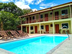 un complexe avec une piscine, des chaises et un bâtiment dans l'établissement Estadia cipó, à La Serra do Cipo