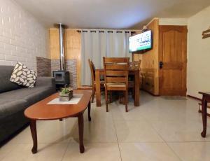 sala de estar con sofá, mesa y TV en Cabañas altos de Mirasol, en Puerto Montt