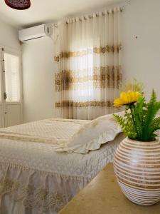 a bedroom with a bed and a vase with flowers in it at Djerba Dar BAYA in Houmt Souk