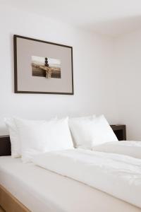1 cama con sábanas blancas y una foto en la pared en Culinaria living, en Tirolo