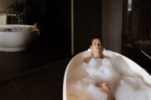 a woman sitting in a bath tub in a bathroom at Culinaria living in Tirolo +68 photos