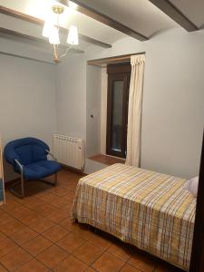 sypialnia z łóżkiem i niebieskim krzesłem w obiekcie CASA RURAL SAN JULIAN w mieście Villahermosa del Río