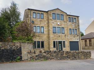 a large brick building with a stone wall at Vista Tasso in Holmfirth