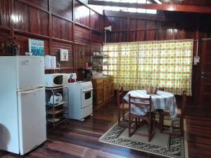 a kitchen with a table and a white refrigerator at Casas Guaney in Manuel Antonio