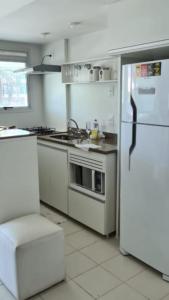 a kitchen with white appliances and a white refrigerator at Maravilhoso flat em Pontal Beach Resort Recreio RJ in Rio de Janeiro