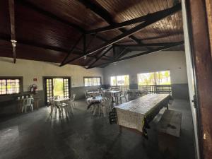 una sala da pranzo con tavoli, sedie e finestre di Chalé Jorai - pé na areia a Bertioga