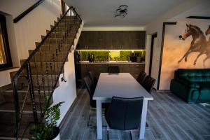 a kitchen with a table and a staircase with a horse on the wall at Hanul Doctorului Badeni-Runcu in Runcu