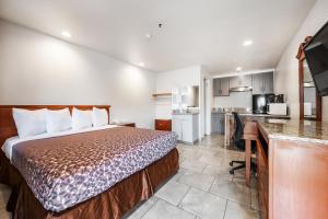 a bedroom with a bed and a desk and a kitchen at City Creek Inn & Suites in Salt Lake City