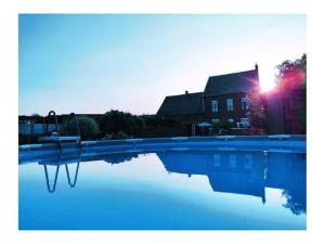 a swimming pool with a swing in front of a house at Gite Au champ du bouillon proche de Pairi Daiza wellness en option in Chièvres