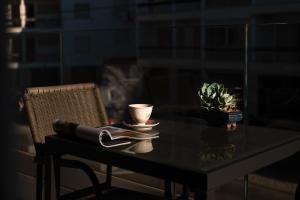 a table with a chair and a cup and a plant at Gold Coast Photography Inn in Estoril