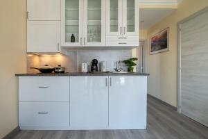a white kitchen with white cabinets and wood floors at Gold Coast Photography Inn in Estoril