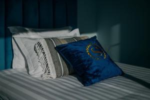 a bed with a blue pillow and white pillows at Gold Coast Photography Inn in Estoril