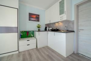 a kitchen with white cabinets and a flat screen tv at Gold Coast Photography Inn in Estoril