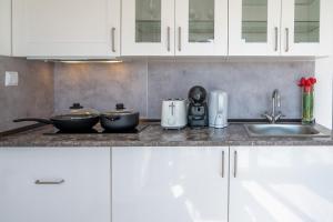 a kitchen counter with white cabinets and a sink at Gold Coast Photography Inn in Estoril