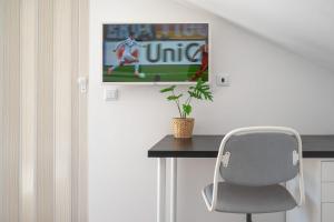 a desk with a chair and a television on a wall at Gold Coast Photography Inn in Estoril