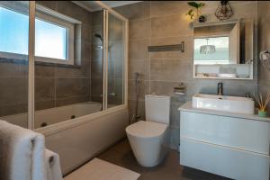 a bathroom with a toilet and a tub and a sink at Gold Coast Photography Inn in Estoril