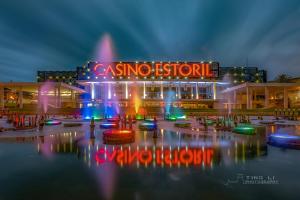 a casino resort with a fountain in the water at night at Gold Coast Photography Inn in Estoril