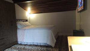 - une chambre avec un lit blanc et un plafond en bois dans l'établissement Pousada Cusco - no Centro Jaraguá do Sul - Sem Estacionamento, à Jaraguá do Sul