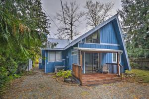 a blue house with a porch and a deck at Riverfront Gold Bar Cabin with Hot Tub and Mtn Views! in Gold Bar