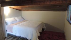 1 dormitorio con cama blanca y techo de madera en Pousada Cusco - no Centro Jaraguá do Sul - Sem Estacionamento, en Jaraguá do Sul