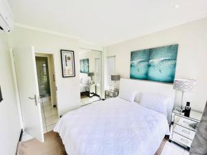 a white bedroom with a large bed and a bathroom at Quebec Apartments - Fully Furnished & Equipped 1 Bedroom Apartment in Sandton +12 photos