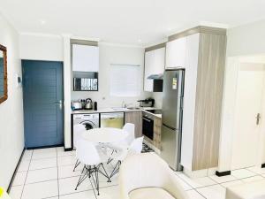a kitchen with a table and white chairs in it at Quebec Apartments - Fully Furnished & Equipped 1 Bedroom Apartment in Sandton