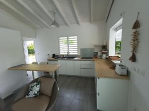 eine Küche mit weißen Schränken und einem Holztisch in der Unterkunft Villa 4 étoiles avec piscine, 3 chambres et jardin tropical in Saint-François