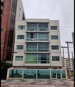 wysoki budynek ze szklanymi oknami w mieście w obiekcie Apartamento de frente para o mar w mieście Guarapari