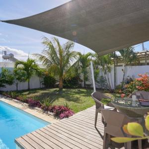Villa Primera 3 bedroom bungalow with private pool Grand Bay في غراند بايَ: فناء مع طاولة وكراسي بجوار حمام سباحة