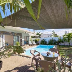 a patio with a pool with a table and chairs at Villa Primera 3 bedroom bungalow with private pool Grand Bay in Grand Baie