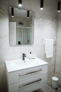 a white bathroom with a sink and a mirror at Hercegovina apartments in Mostar