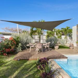 eine Terrasse mit einem Tisch und Stühlen neben einem Pool in der Unterkunft Villa Primera 3 bedroom bungalow with private pool Grand Bay in Grand Baie